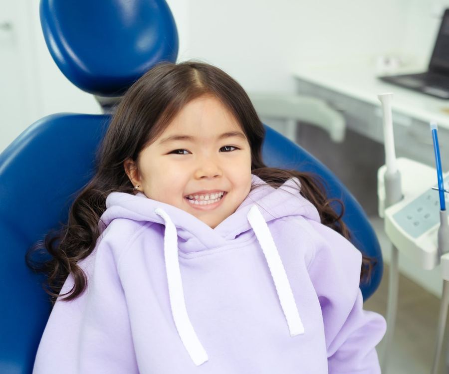 A young girl smiling in a dental chair before her visit